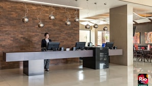 Un espace d’accueil d’hôtel au design moderne, avec un mur en briques, un long comptoir d’accueil et plusieurs postes informatiques.