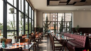 Un vaste espace d édié à la salle à manger, doté de hauts plafonds, de grandes fenêtres et de différents types de sièges, notamment des tables et un long banc.