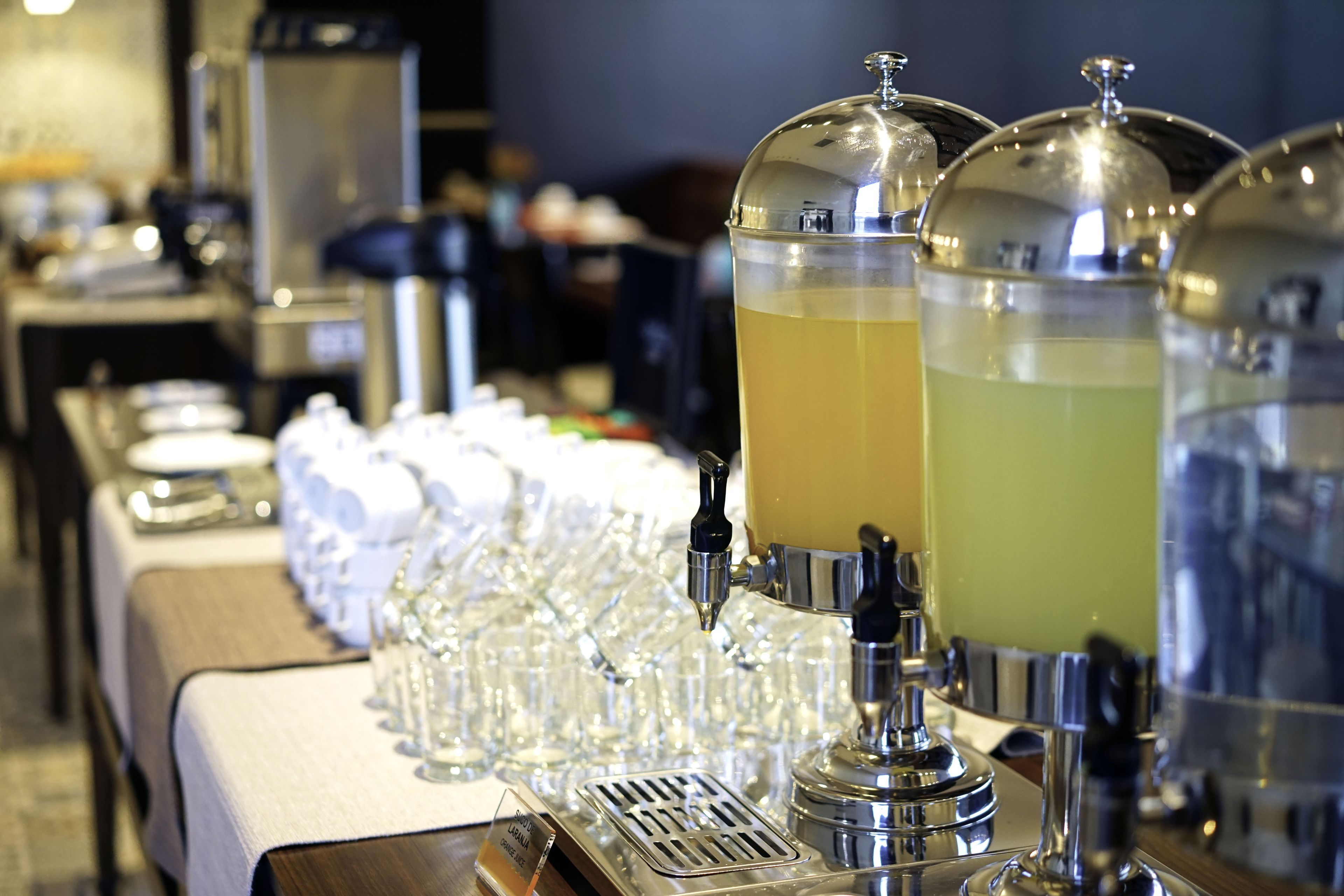 Una estación de bebidas con varios dispensadores y vasos alineados sobre una mesa.