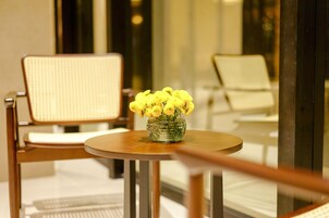 Un interior moderno con una mesa redonda, un jarrón de flores amarillas y dos sillas con respaldo tejido.