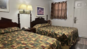 A hotel room with two beds, a nightstand, a lamp, a framed picture, and a door.