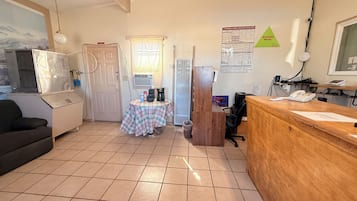 A kitchen with a coffee maker, a refrigerator, and a table with a plaid tablecloth.