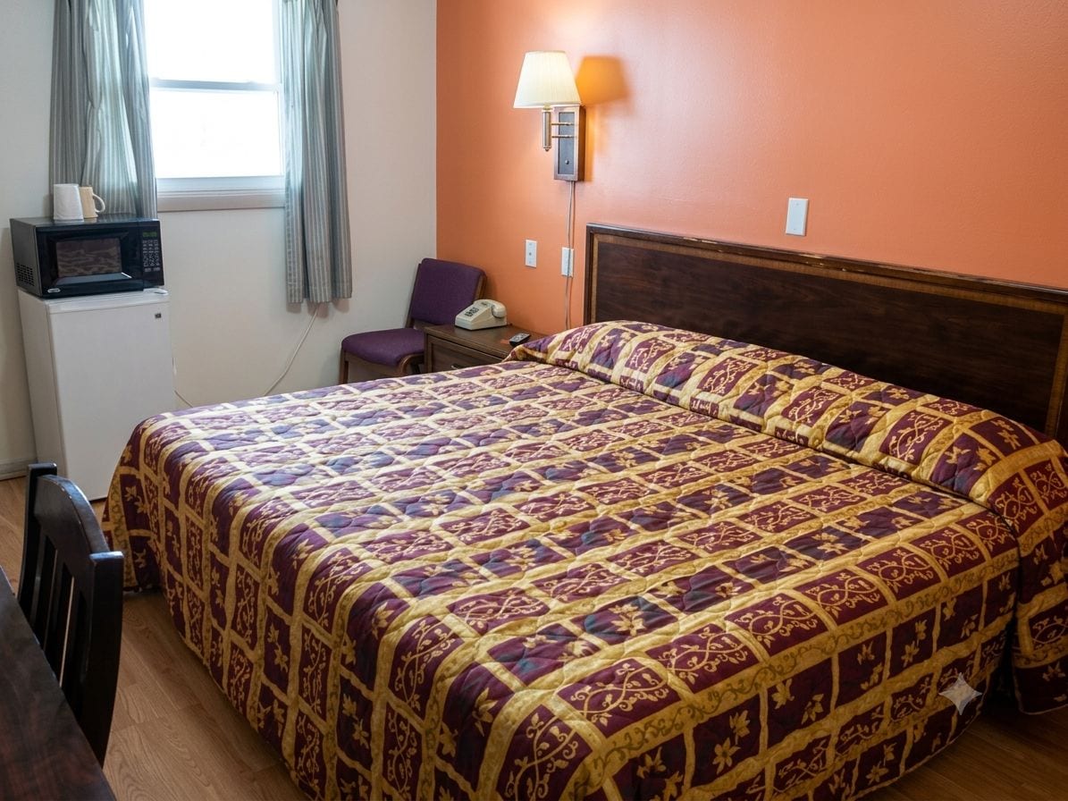 Ein Hotelzimmer mit einem Bett, einem Sessel, einem Schreibtisch, einer Mikrowelle und einer Lampe.