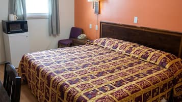 Ein Hotelzimmer mit einem Bett, einem Sessel, einem Schreibtisch, einer Mikrowelle und einer Lampe.