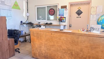A reception desk with a computer, phone, and various informational posters.
