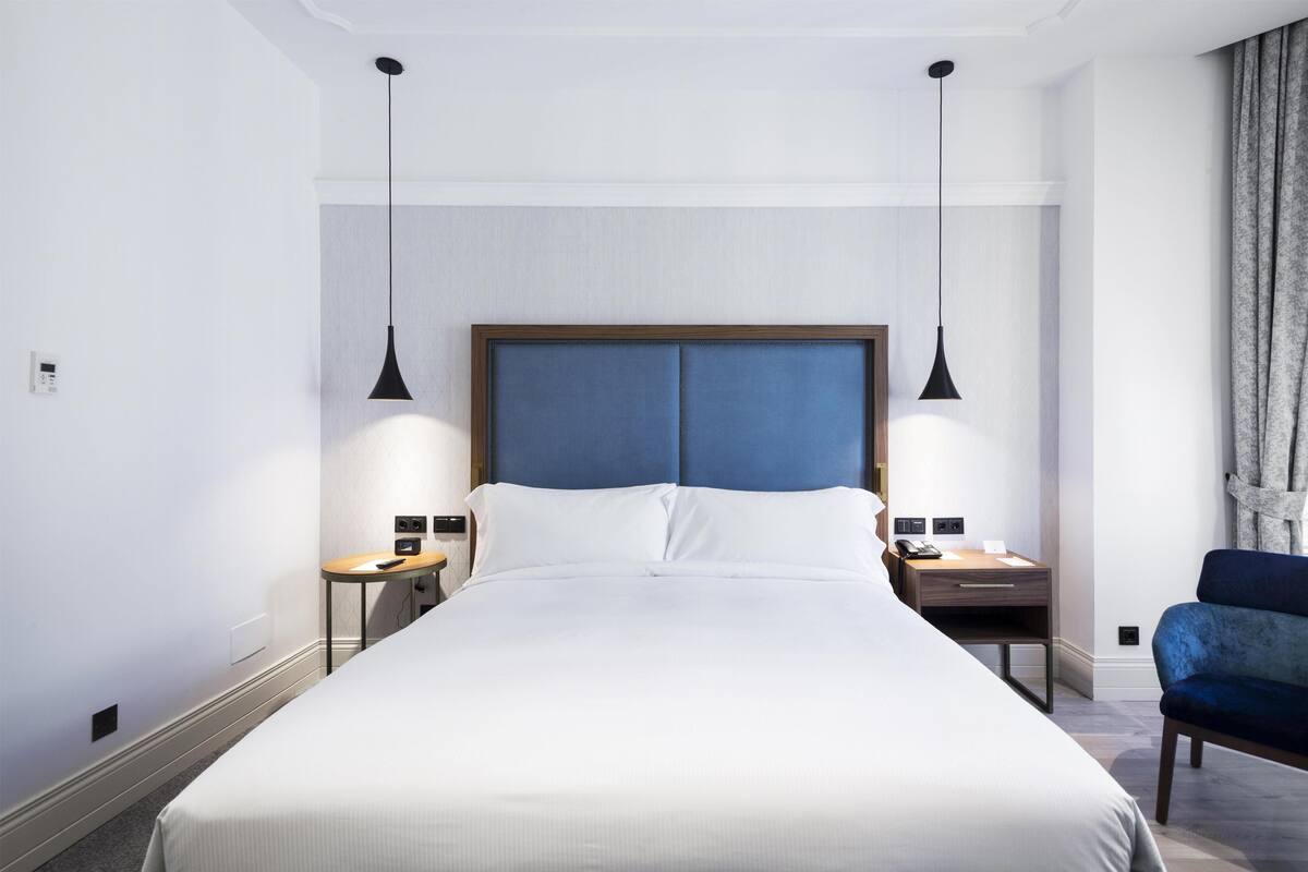 A hotel room with a large bed, two bedside tables, a desk, and a chair.