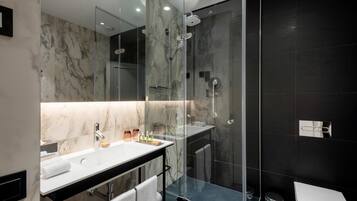 A modern bathroom with a marble vanity, a glass-enclosed shower, and a white toilet.