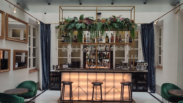 A bar area with a marble countertop, bar stools, and a variety of bottles and glasses. - DoubleTree by Hilton Madrid-Prado (Madrid)