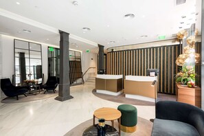 Experience the sleek lobby with a reception desk, comfortable seating area, and a grand staircase.