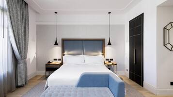 Una habitació d'hotel moderna amb un llit gran, taules de nit, un escriptori i un armari.