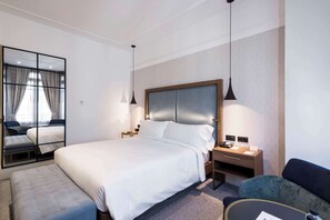 Relax in comfort with a large bed, nightstand, and seating area, plus a large mirror and recessed ceiling.
