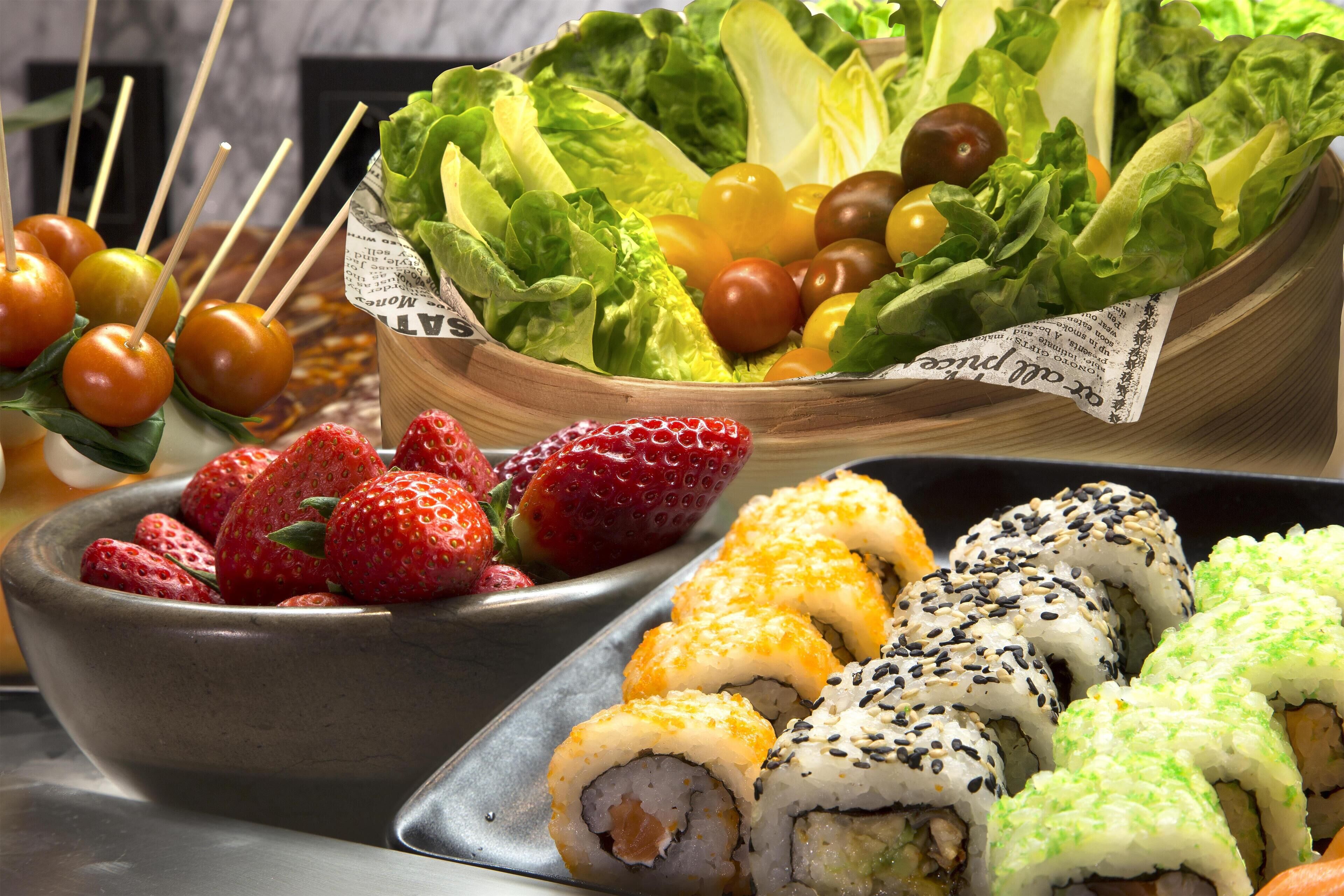 Variedad de alimentos, entre ellos sushi, fresas y tomates cherry.