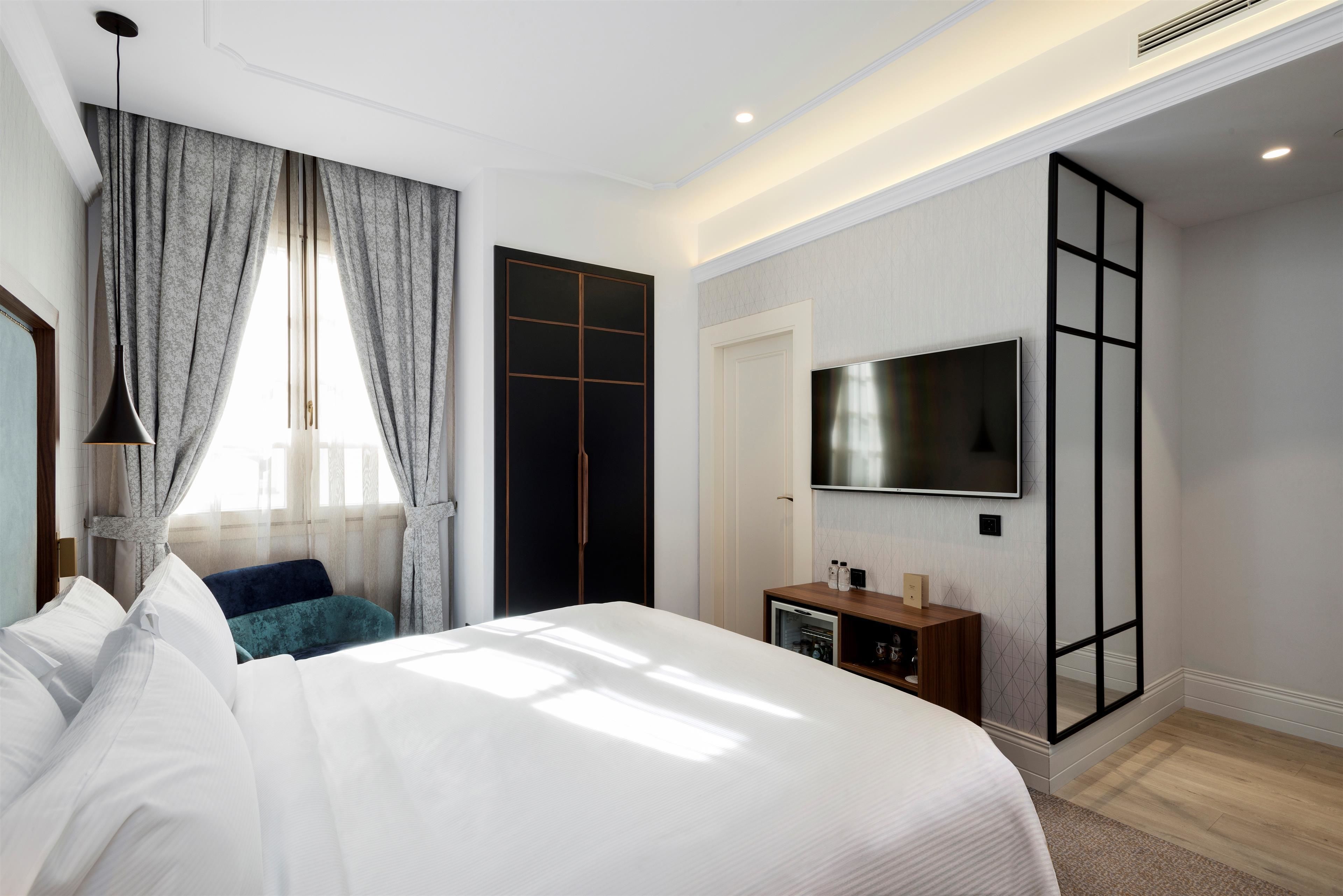Una habitación de hotel moderna con una cama grande, un televisor montado en la pared y un armario con puerta corredera.