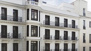 A multi-story building with a white facade, multiple balconies, and a storefront with signage. - DoubleTree by Hilton Madrid-Prado (Madrid)