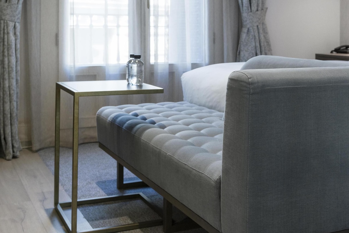A modern bedroom with a bed, a small table, and curtains.