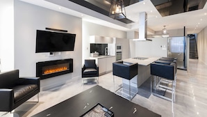 A modern living room with a fireplace, a flat-screen TV, and a dining area with bar stools. - Hotel Milton-Parc (Montreal)