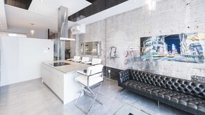 A modern kitchen with a central island, white cabinetry, and a black leather sofa. - Hotel Milton-Parc (Montreal)