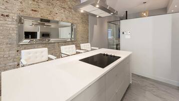 A modern kitchen with a large island, white cabinetry, and a brick accent wall.