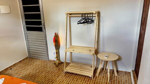 A room with a wooden shelf unit with hooks, a small round table, and a decorative item on the floor. - Pousada Maresia Centro (Ipojuca)