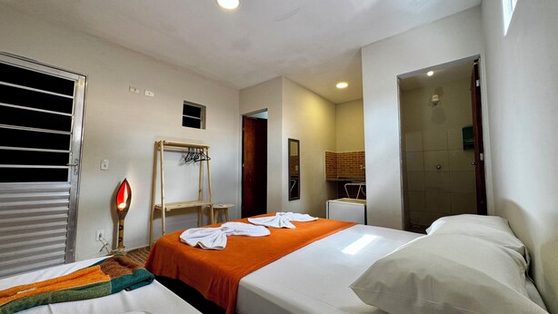 A hotel room with two beds, a wooden drying rack, a mirror, and a small bathroom visible through an open door. - Pousada Maresia Centro (Ipojuca)