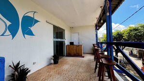 A covered outdoor area with a wooden reception desk, a tiled floor, and a blue railing. - Pousada Maresia Centro (Ipojuca)