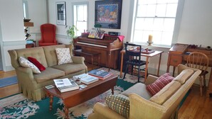 A living room with a sofa, armchair, coffee table, and a piano. - The Farmstand Bed & Breakfast (Chocorua)