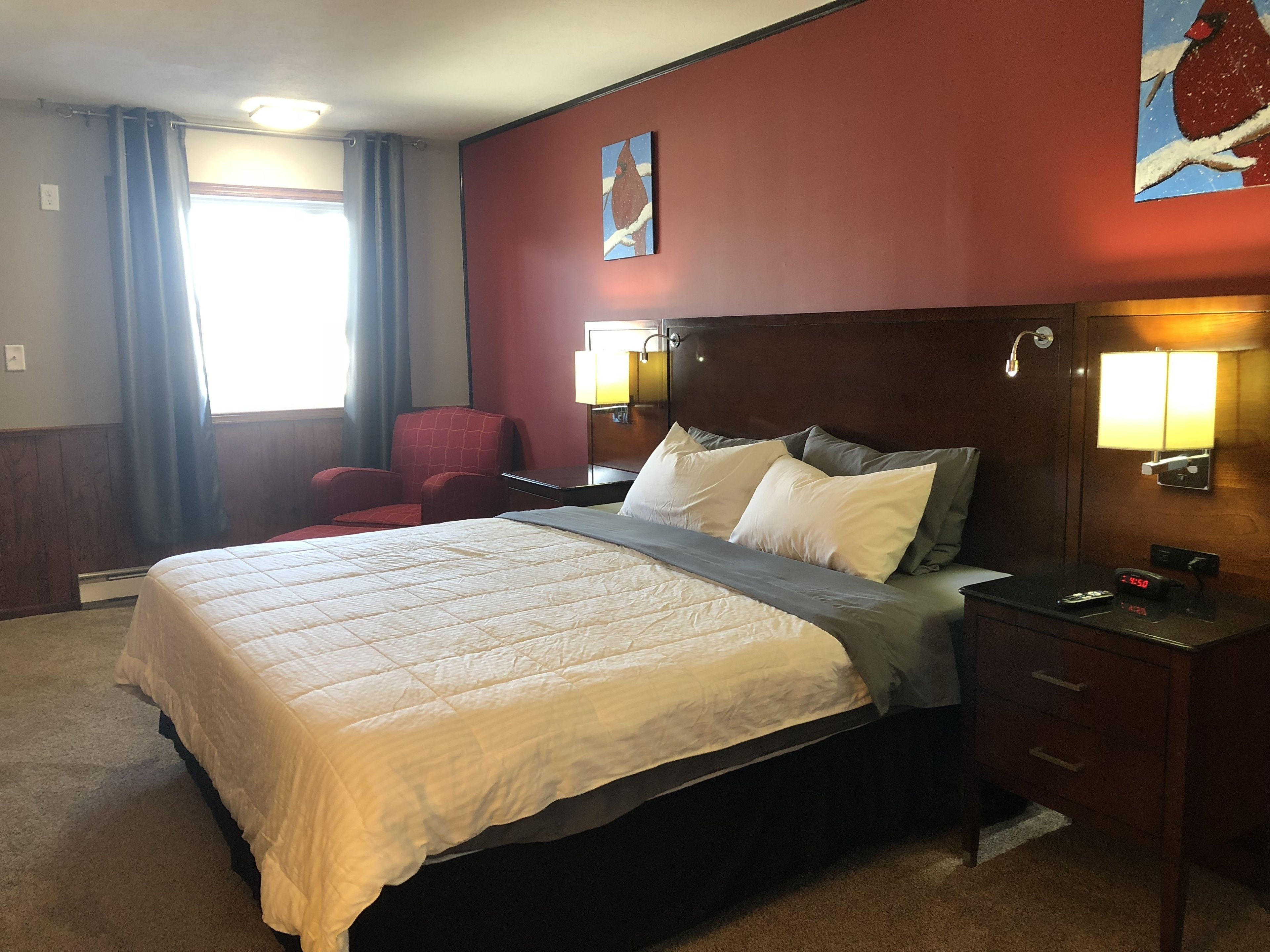Une chambre d’hôtel avec un grand lit, un bureau avec une lampe, une chaise et un tableau au mur.