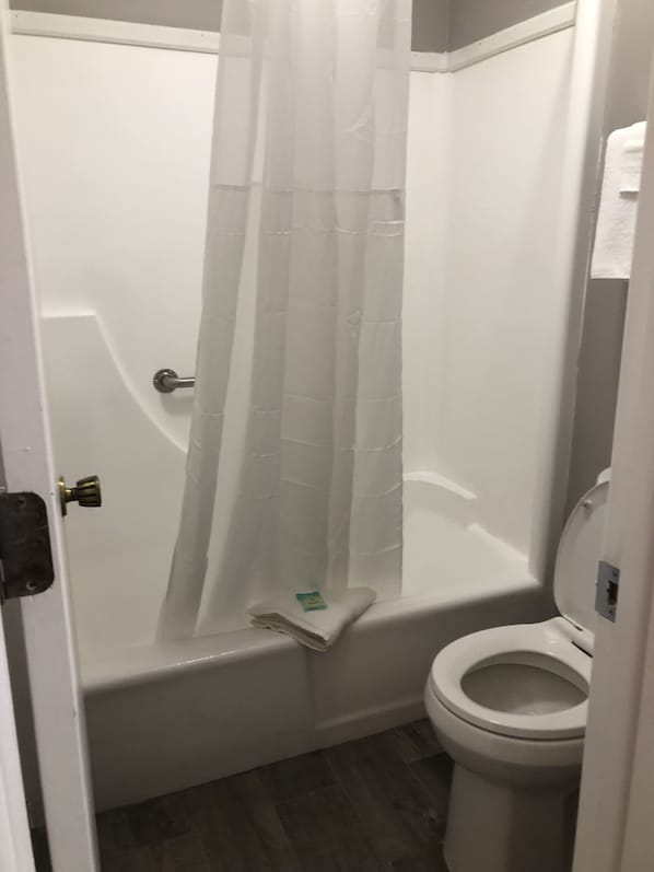 Un baño con ducha, inodoro y una toalla en el suelo.