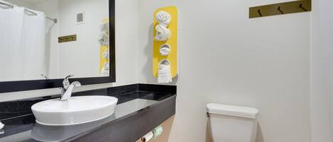 A bathroom with a white sink, a mirror, and a toilet.