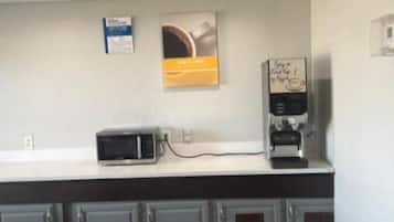 A kitchenette with a microwave, coffee machine, and cabinets.