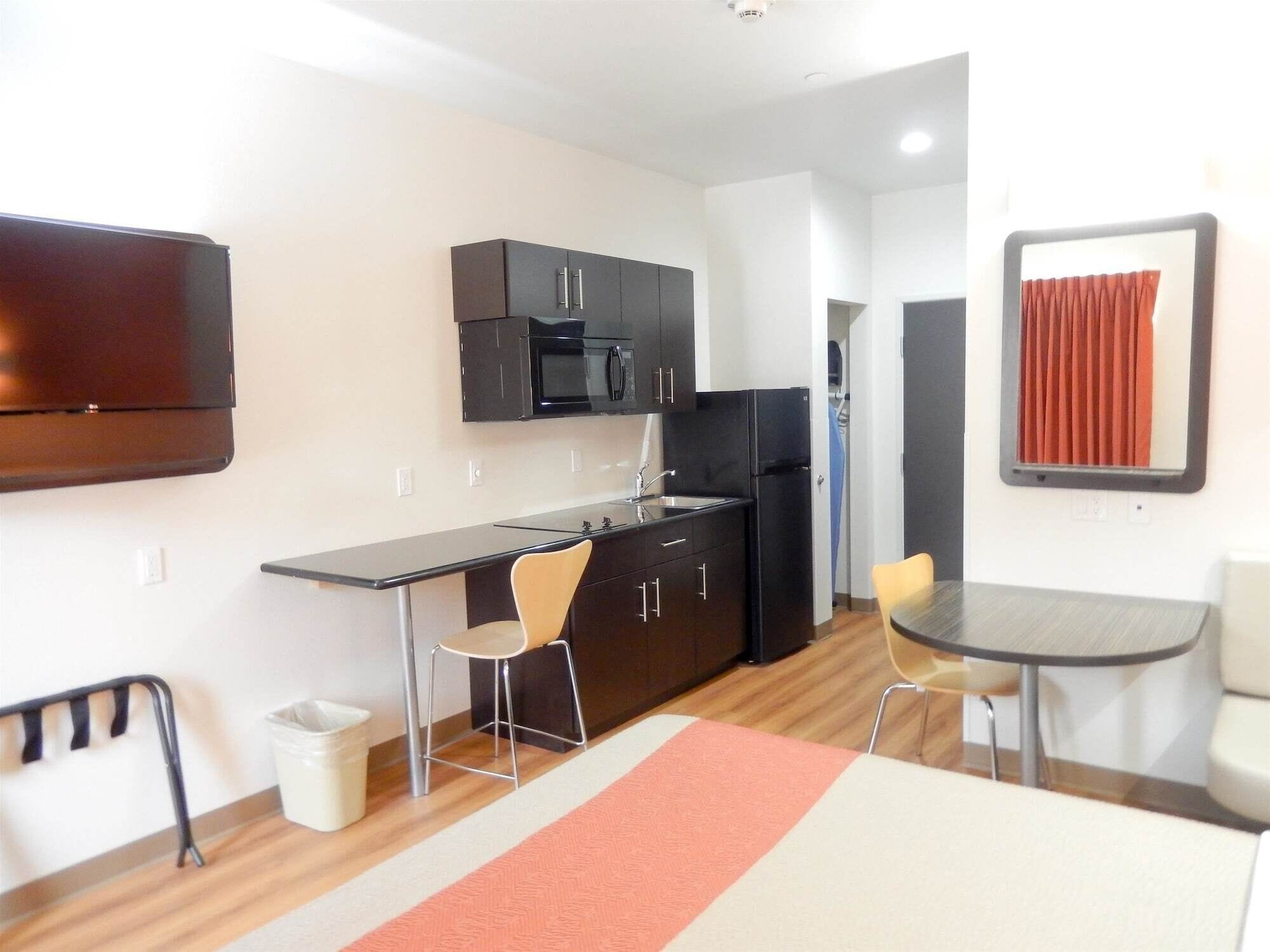 A compact kitchen with a microwave, refrigerator, and a small dining area with two chairs and a table.