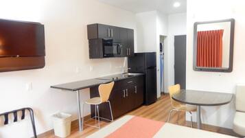 A compact kitchen with a microwave, refrigerator, and a small dining area with two chairs and a table.