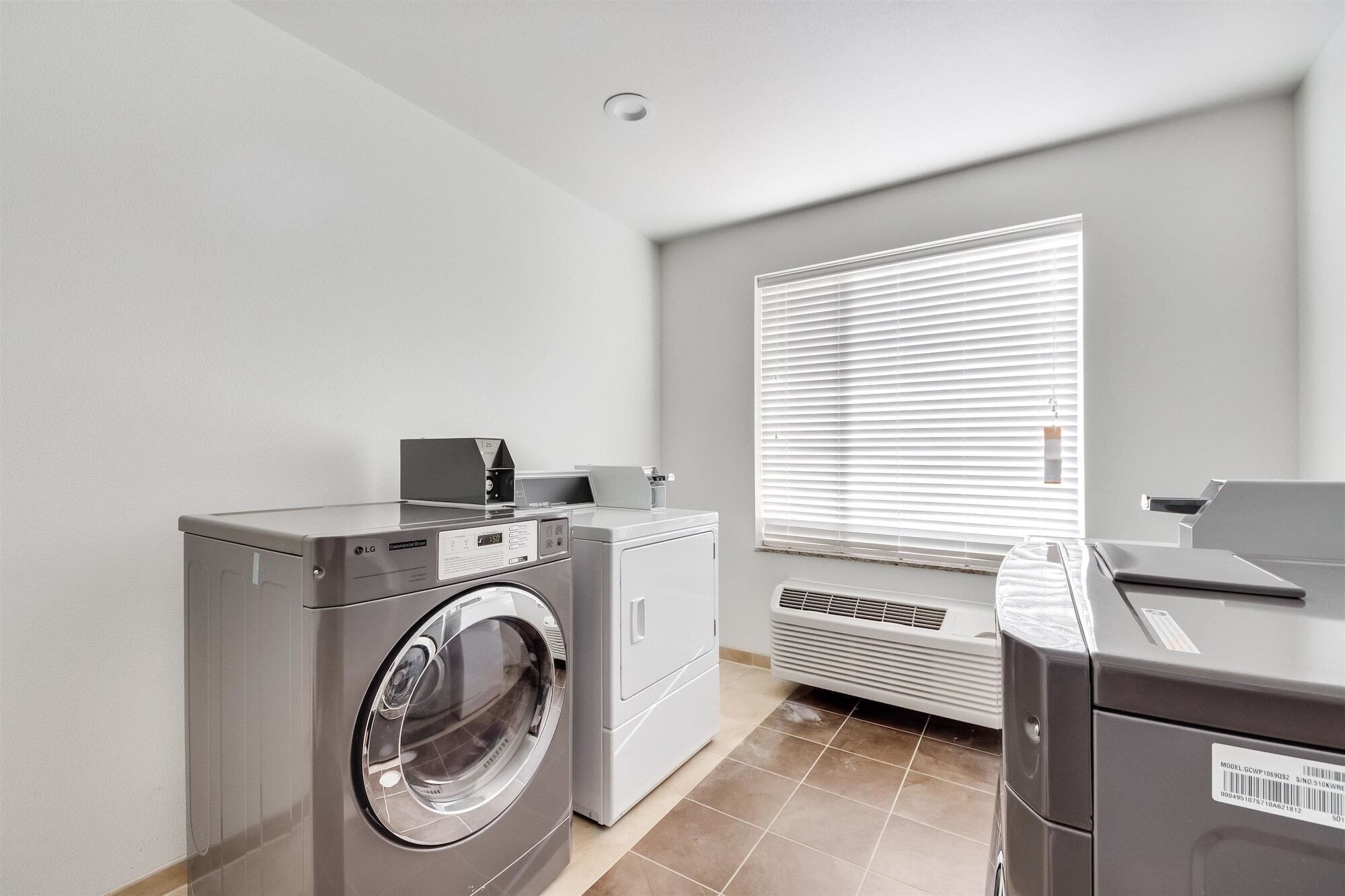 Une buanderie équipée d’un lave-linge, d’un sèche-linge et d’une table à repasser.