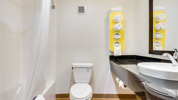 A modern bathroom with a white toilet, a yellow towel rack, a sink, and a mirror.