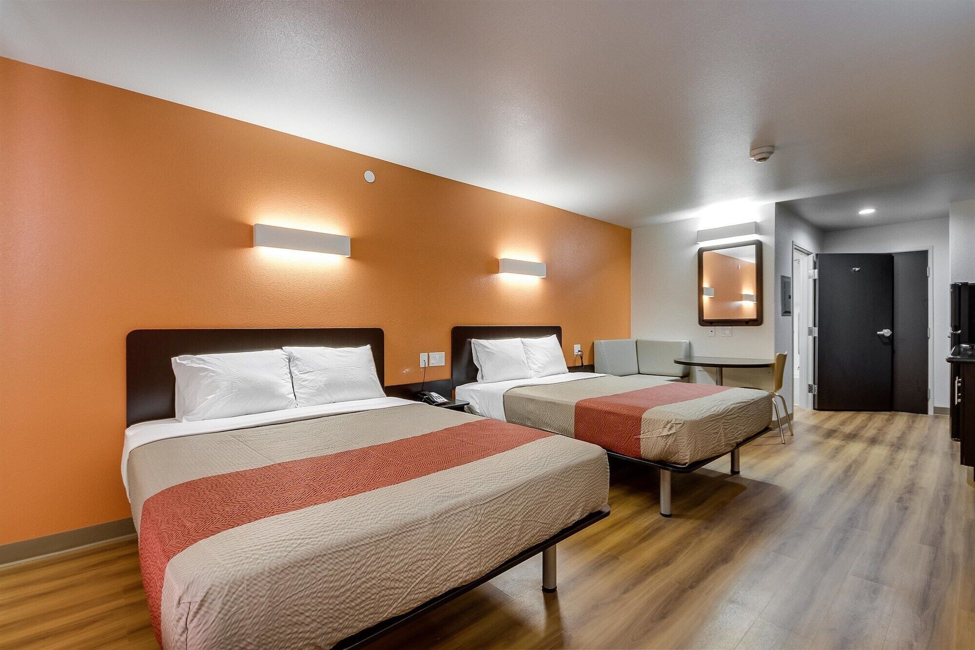 Une chambre d’hôtel avec deux lits, une petite table, une chaise et une porte.