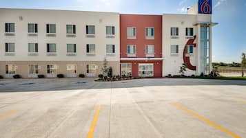 A modern hotel with a flat facade, multiple windows, and a large parking lot.