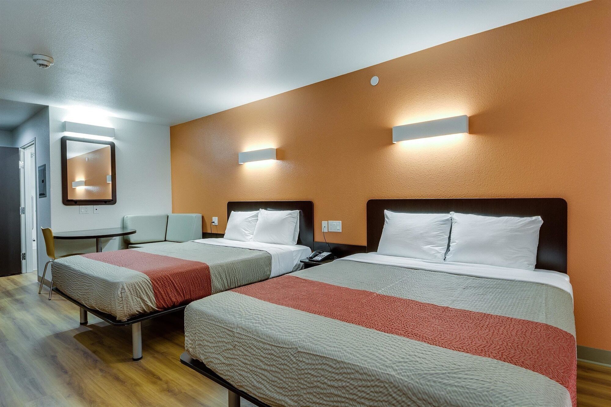 A hotel room with two beds, a small table, and a chair.
