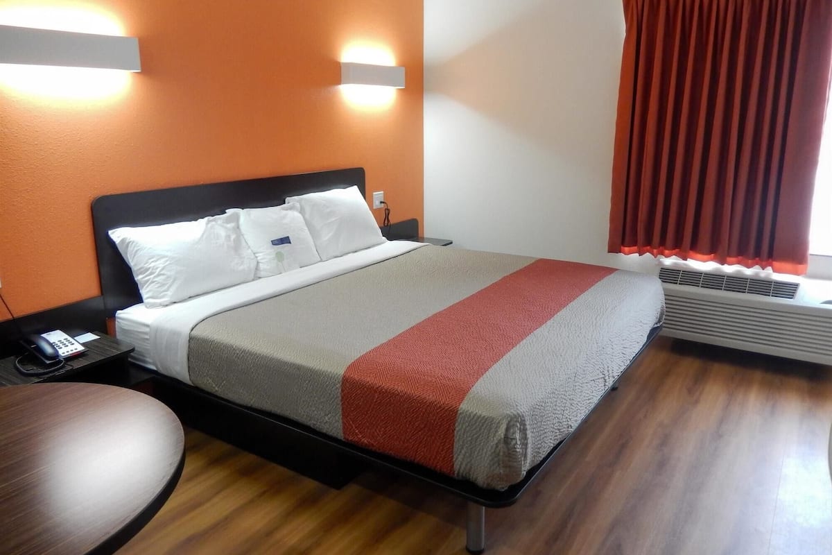 A hotel room with a bed, bedside table, and a chair.