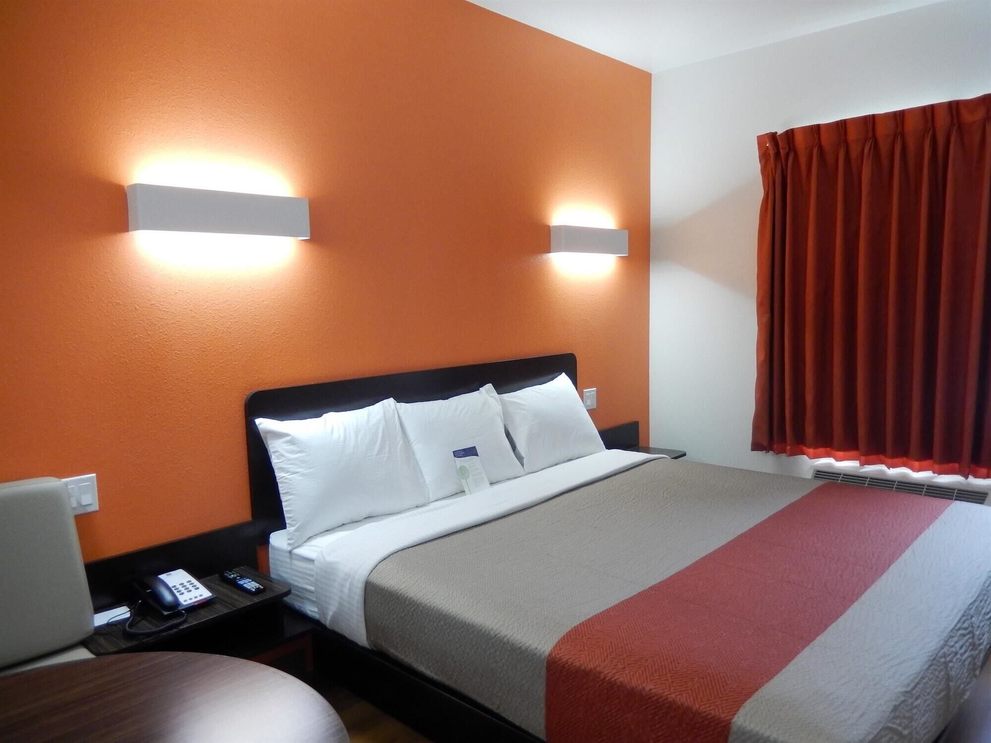 A hotel room with a bed, a desk with a telephone, and a chair.