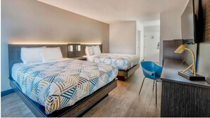 Ett modernt hotellrum med två sängar, ett skrivbord och en stol.