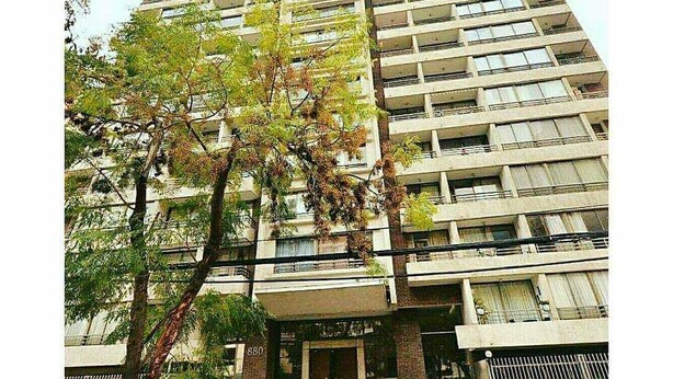 Um edifício alto com várias varandas e uma árvore na frente.