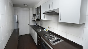 Uma cozinha moderna com armários brancos, uma pia de aço inoxidável e um fogão a gás.