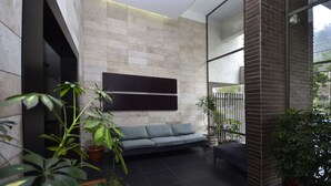 Um interior moderno com sofá cinzento, plantas em vasos e uma janela grande.