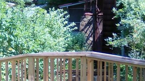 Un puente de madera sobre una pequeña fuente acuática con una noria grande al fondo.