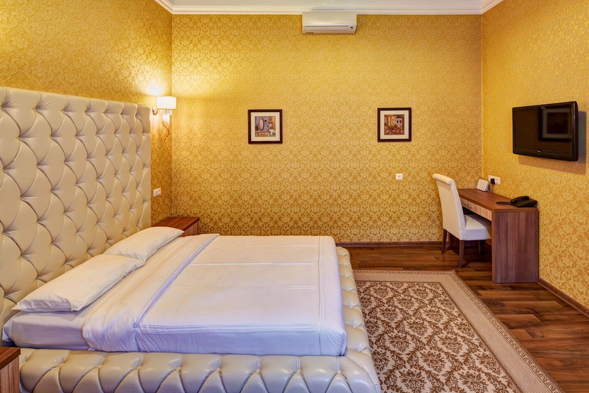A hotel room with a large bed, a desk, and a television.