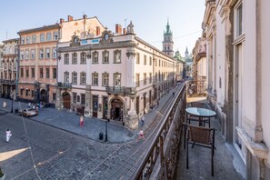 A cobblestone street with historic buildings, a tram line, and a balcony with wicker furniture. - Lviv Apartments (Lviv)