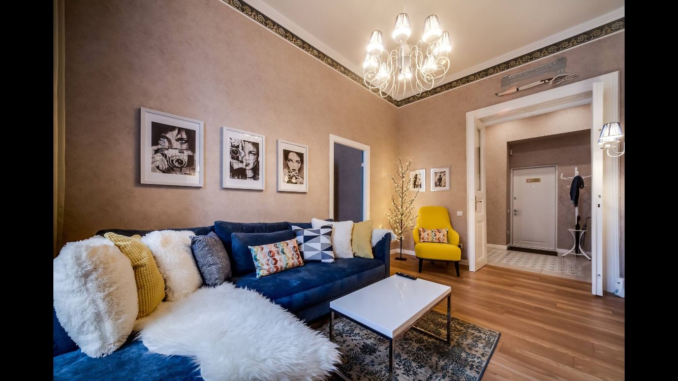 A living room with a blue sofa, a white coffee table, and a yellow armchair.