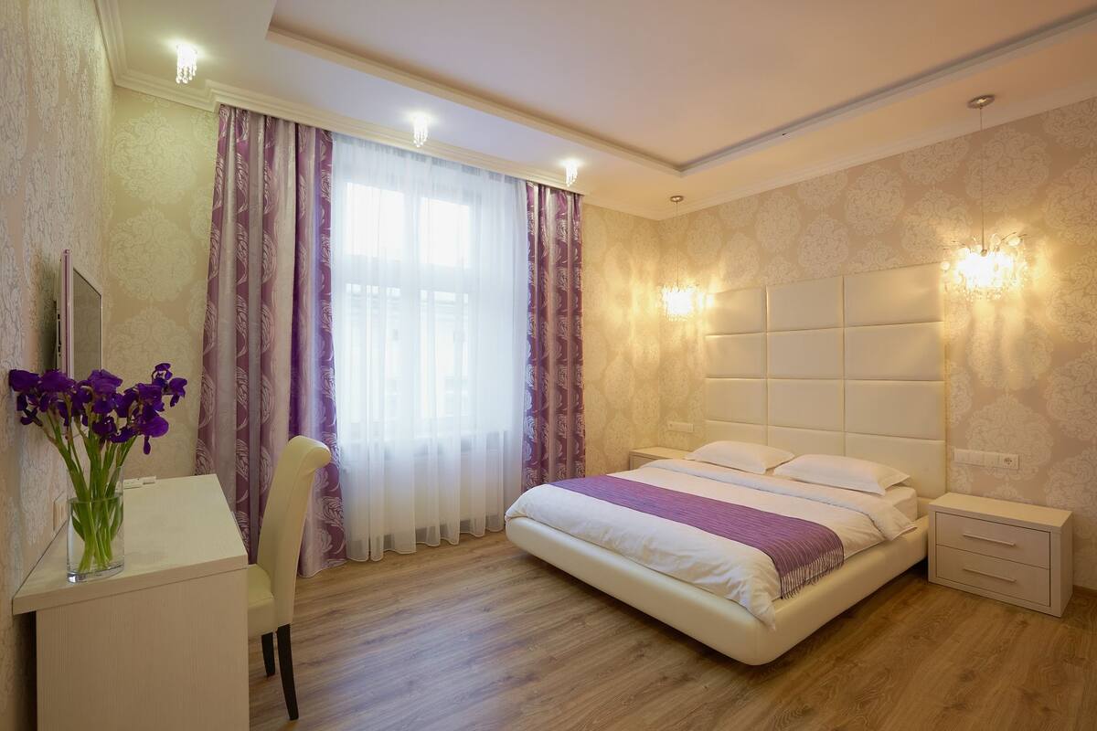 A bedroom with a bed, bedside tables, a desk, and a chair.