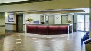 A reception area with a marble floor, a reception desk, and a clock on the wall.