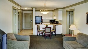 A compact living space with a kitchenette, a dining area, and a seating area with two sofas and a TV.
